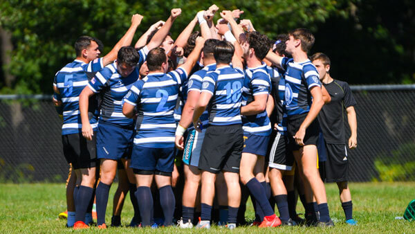 The club rugby players huddle in a cheer