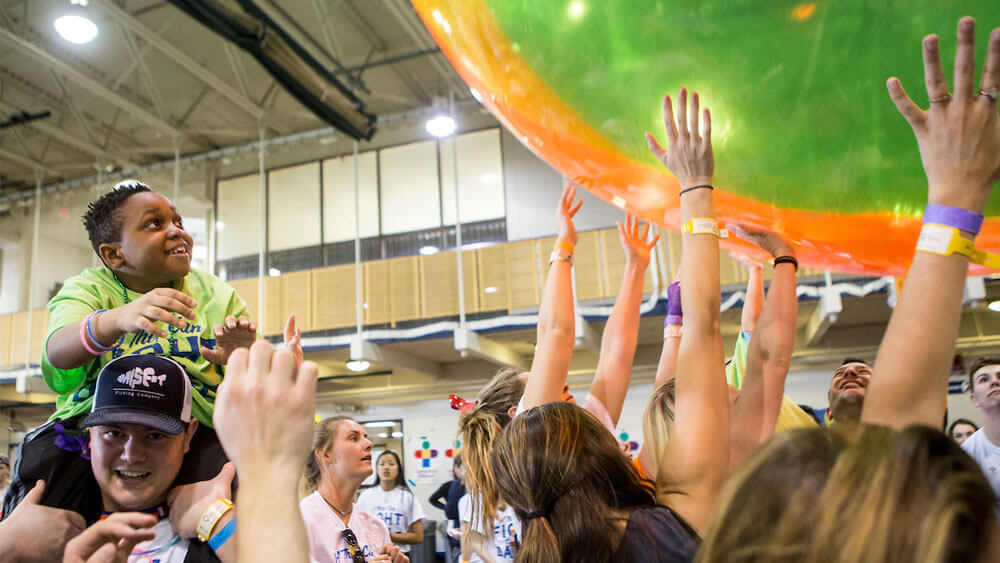 Shemar Williams, 11, a patient at Connecticut Children's Medical Center, sits atop Nate O'Shea, Quinnipiac sophomore, while students threw a giant beach ball within the crowd at QTHON, a Dance Marathon and nationwide movement involving 150 college and high schools which raises money for the Children's Miracle Network Hospital in their communities. Connectciut Children's Medical Center in Hartford benefits from the fundraiser at QTHON in Quinnipiac's University Recreation Center