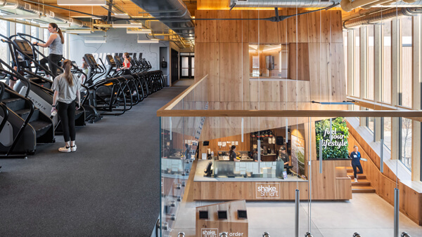 Students exercise on top floor while students walk past Shake Smart smoothie station on first floor