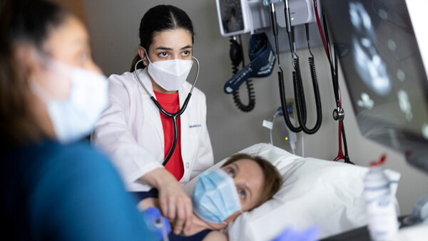 Nursing student uses a stethoscope on a patient.