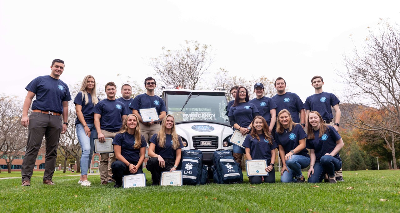 QU EMS members smiling standing next to QU EMS club car