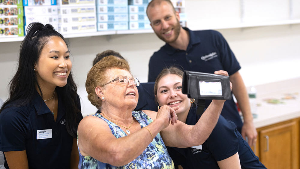 Three Quinnipiac students take a selfie with a senior citizen while volunteering at a senior center