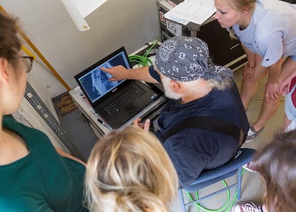 A professor and students examine a coffin scan on a computer