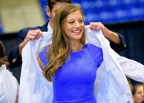 Student receives her coat from a professor during the medical school's White Coat Ceremony