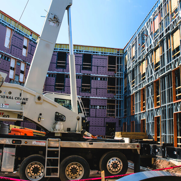 A crane lifts materials in front of a building being constructed in Quinnipiac's South Quad