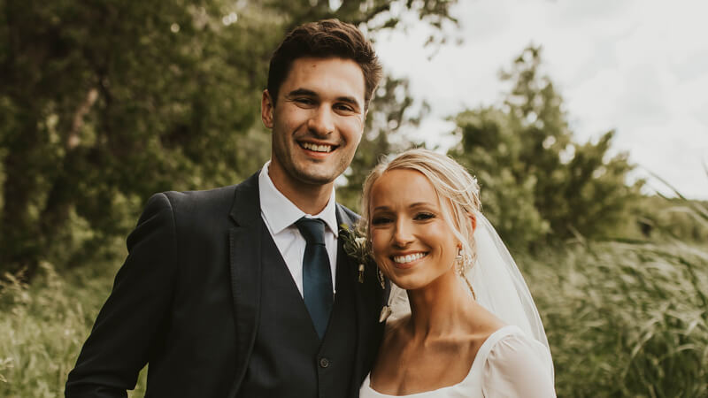 Jordan Weiss Wolak and Andrew Wolak smile in a field on their wedding day