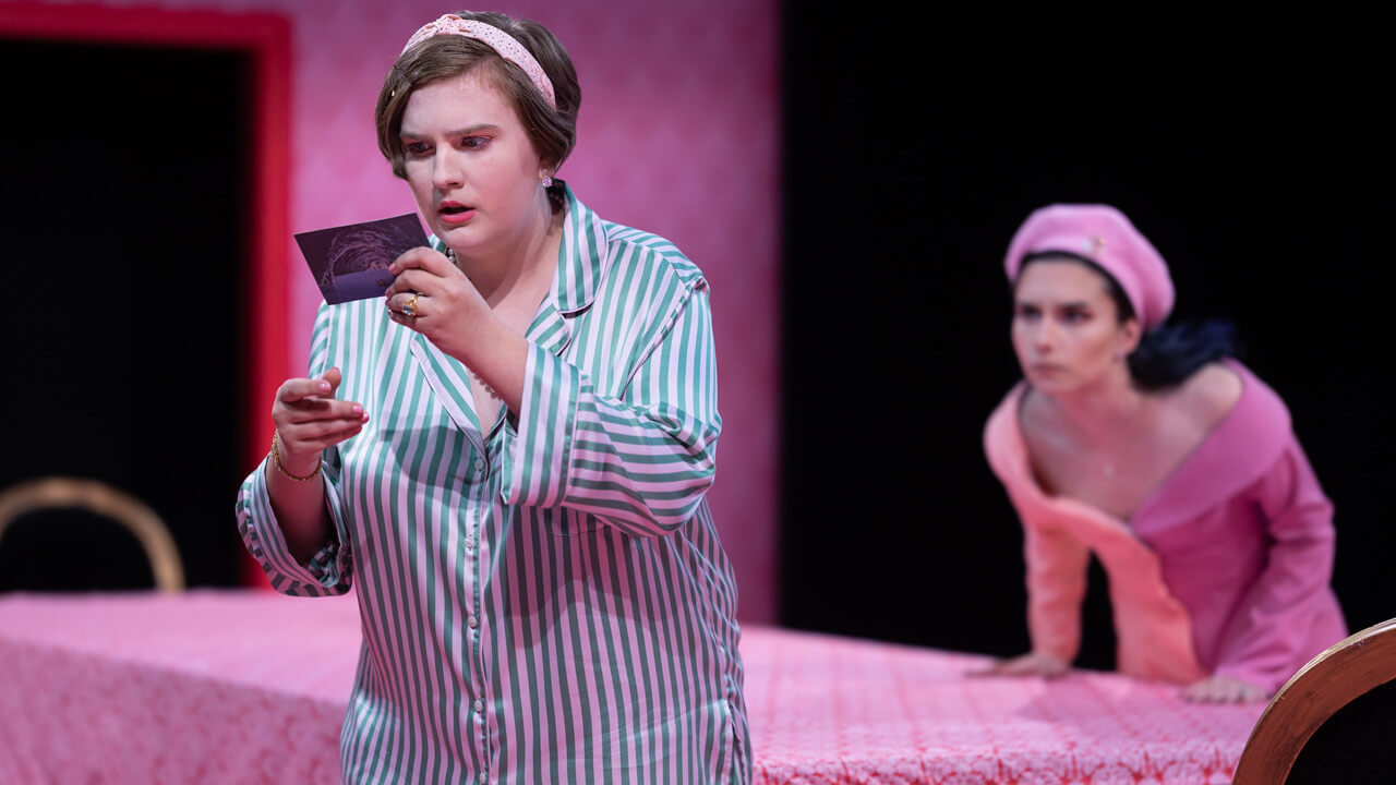 A female student actress looking at a postcard on stage